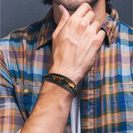Men's braided leather bracelet with tiger eye stone, worn with plaid shirt for casual luxury style.