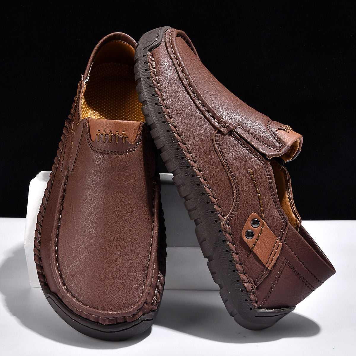Brown leather loafers with hand-stitched detailing and textured sole, minimalist men's footwear design