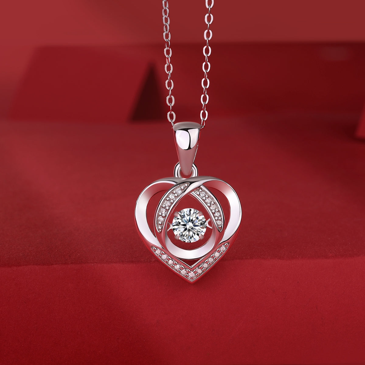Elegant heart-shaped pendant necklace with sparkling diamond centerpiece and crystal accents on red velvet