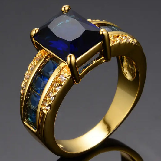 Luxury gold ring with large blue crystal and crystal accents, minimalist design