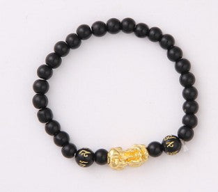 Black beaded bracelet with gold Buddha charm, minimalist luxury jewelry design
