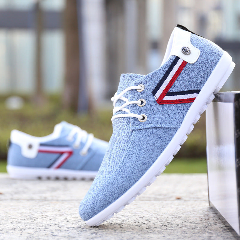 Light blue canvas sneakers with red and navy stripe, white laces, and rubber sole — minimalist casual footwear