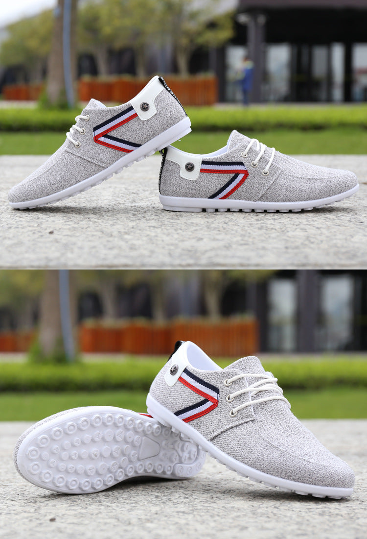 Gray casual sneakers with red, white, and blue stripe, white laces, and textured sole on outdoor pavement