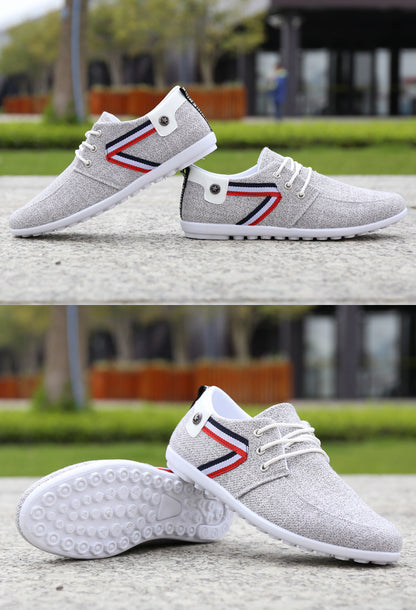 Gray casual sneakers with red, white, and blue stripe, white laces, and textured sole on outdoor pavement