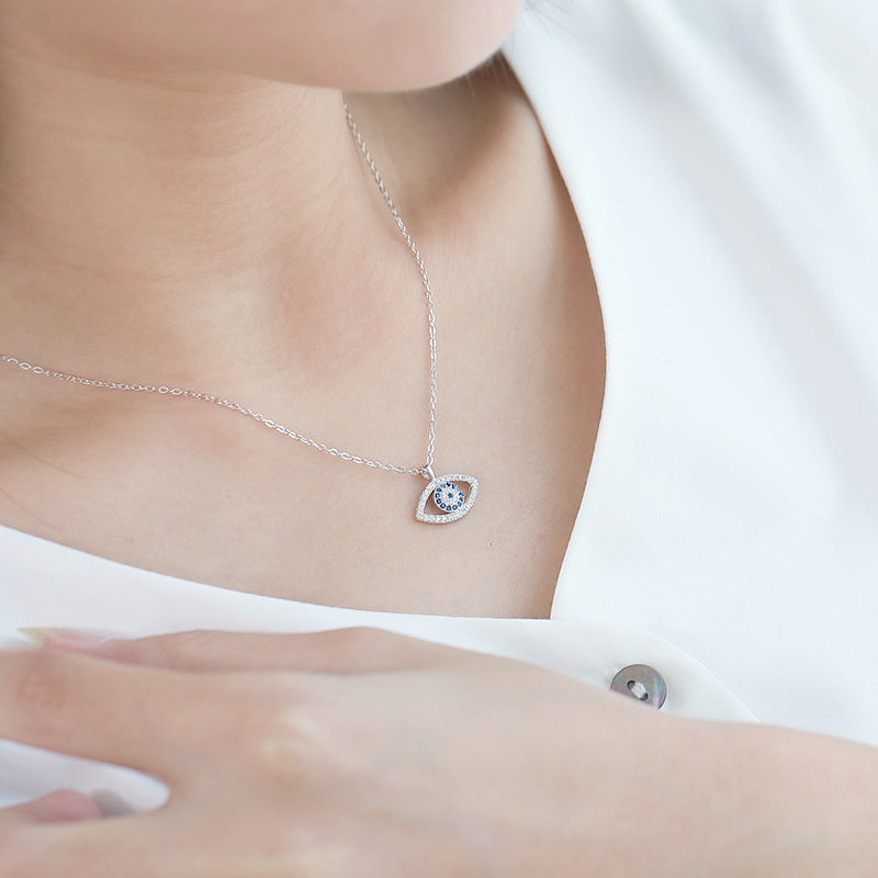 Delicate silver evil eye necklace with blue center and crystal accents, worn on model