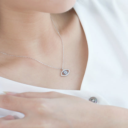 Delicate silver evil eye necklace with blue center and crystal accents, worn on model