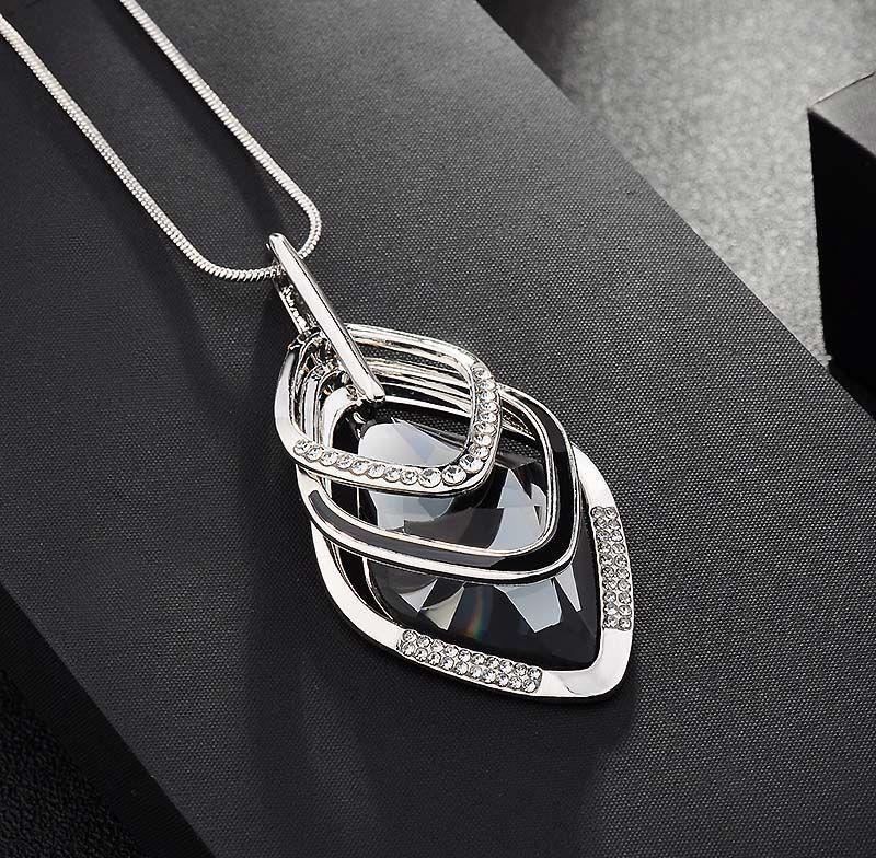 Luxury silver pendant with black crystal and diamond accents, minimalist design on black fabric