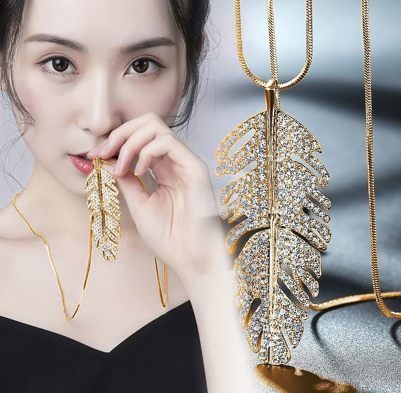 Gold leaf pendant necklace with crystal embellishments, minimalist luxury jewelry design