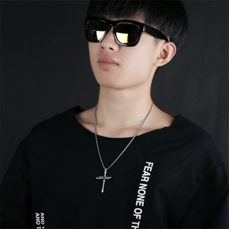 Man wearing black sunglasses and silver cross necklace, minimalist luxury accessory