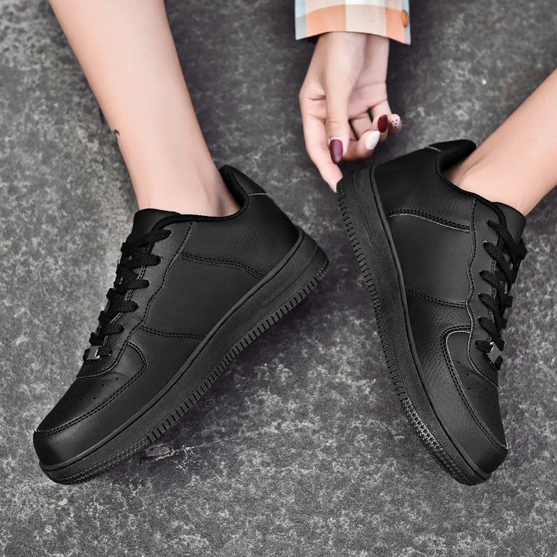 Black minimalist leather sneakers with chunky sole, styled with plaid sleeve on textured gray background