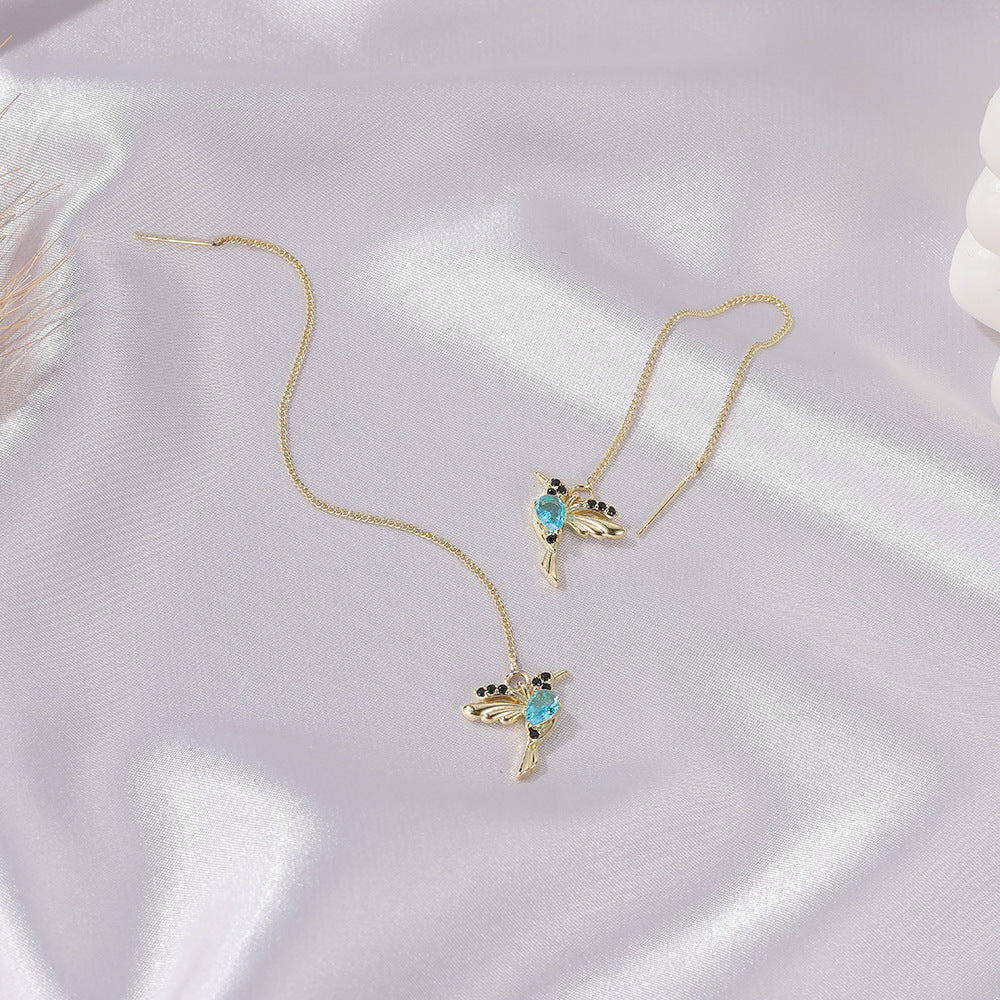 Gold hummingbird earrings with blue gemstones on satin, luxury minimalist jewelry