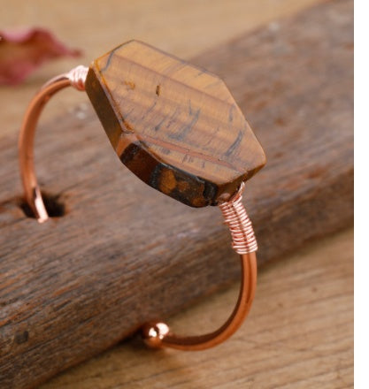 Copper wire-wrapped tiger's eye stone bracelet on rustic wood — minimalist luxury jewelry