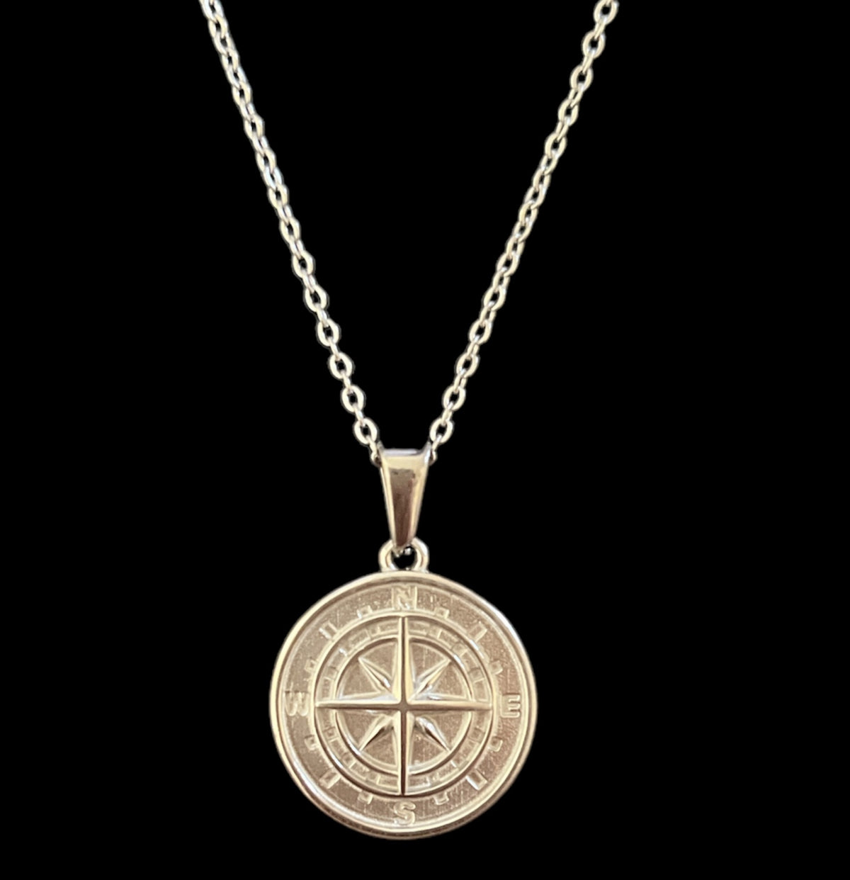 Gold compass pendant necklace with minimalist design, luxury jewelry piece on chain against black background