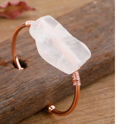 Rose quartz stone bangle with copper wire wrap, minimalist luxury jewelry on rustic wood