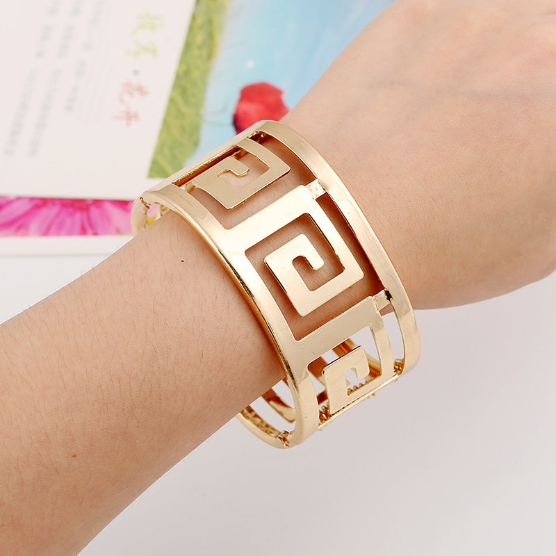 Gold Greek key cuff bracelet on wrist, minimalist luxury jewelry design