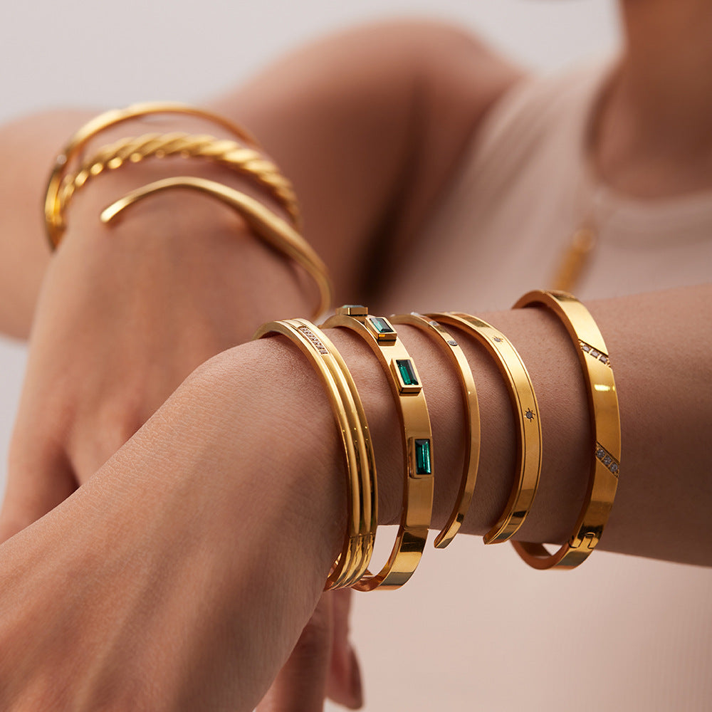 Layered gold bangles with emerald accents and minimalist design, luxury jewelry collection