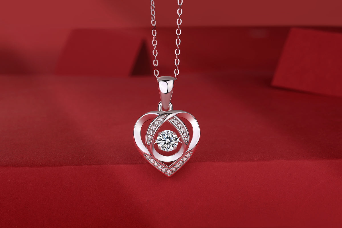 Elegant heart-shaped pendant necklace with sparkling diamond center and crystal accents on red velvet