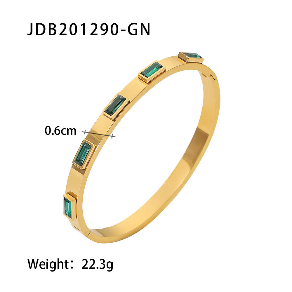 Gold bangle with emerald-cut green stones, minimalist luxury jewelry design