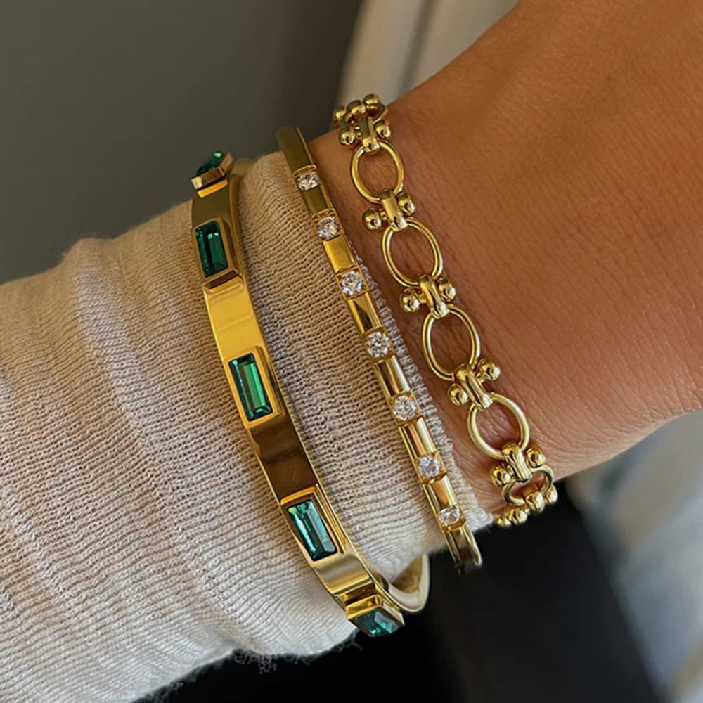 Gold bracelets with emerald and diamond accents, minimalist luxury jewelry stack on wrist