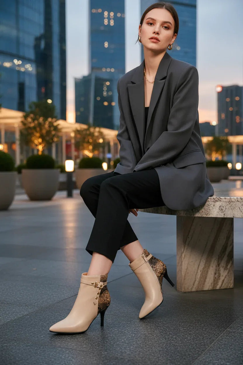 Beige ankle boots with snake print heel and buckle detail, styled with gray blazer and black pants in city setting